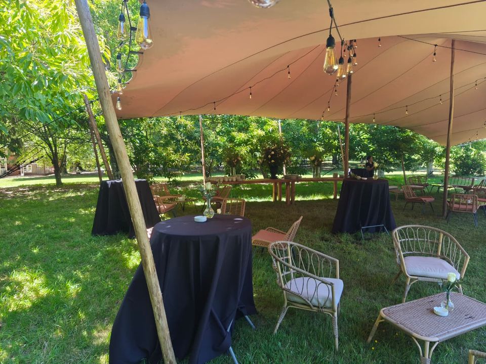 Cena de evento con iluminación cálida bajo una carpa tensada